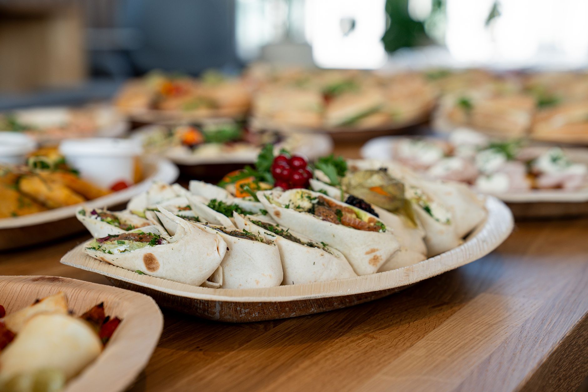 Eine Holzplatte mit verschiedenen vegetarischen Wraps, die frisch zubereitet und halbiert angerichtet sind.