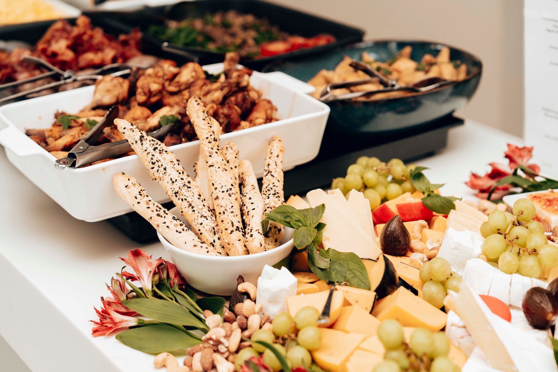 Eine Auswahl an Käsesorten, Gebäck und frischen Zutaten, die auf einer Platte für ein Catering-Event angerichtet sind.