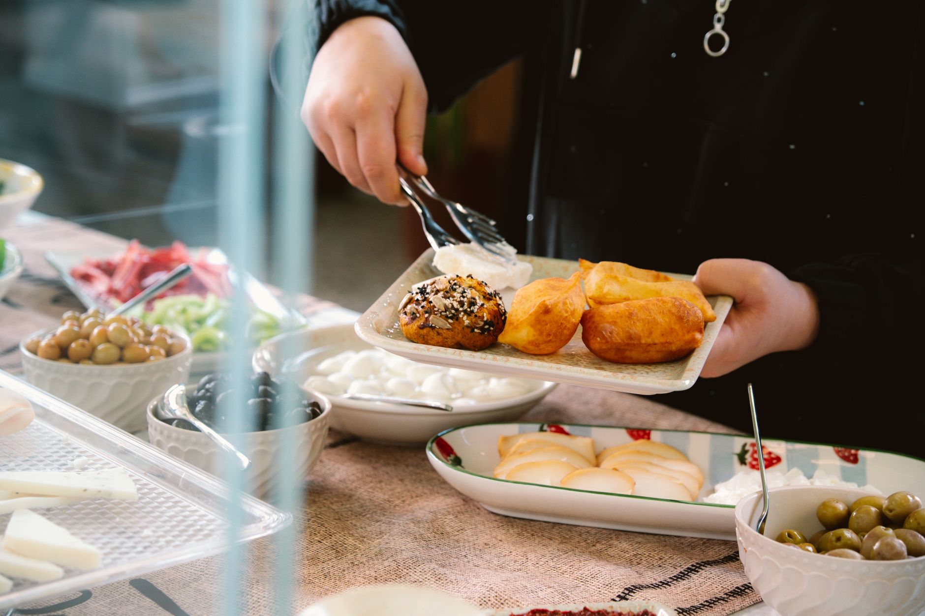 Ein reichhaltig gedecktes Frühstücksbuffet mit Oliven, frischem Brot, Aufstrichen und Tomaten in kleinen Schüsseln