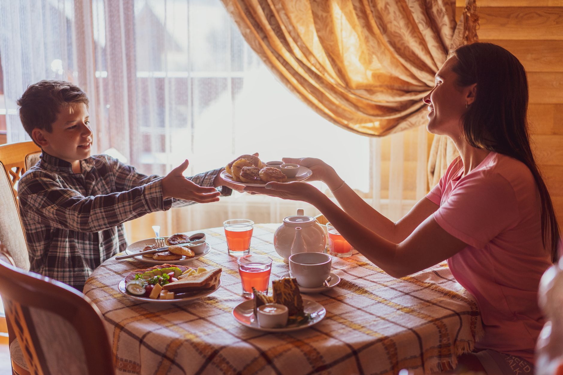 Eine Mutter und ihr Sohn sitzen an einem gemütlichen Frühstückstisch und teilen sich frische Speisen am Morgen