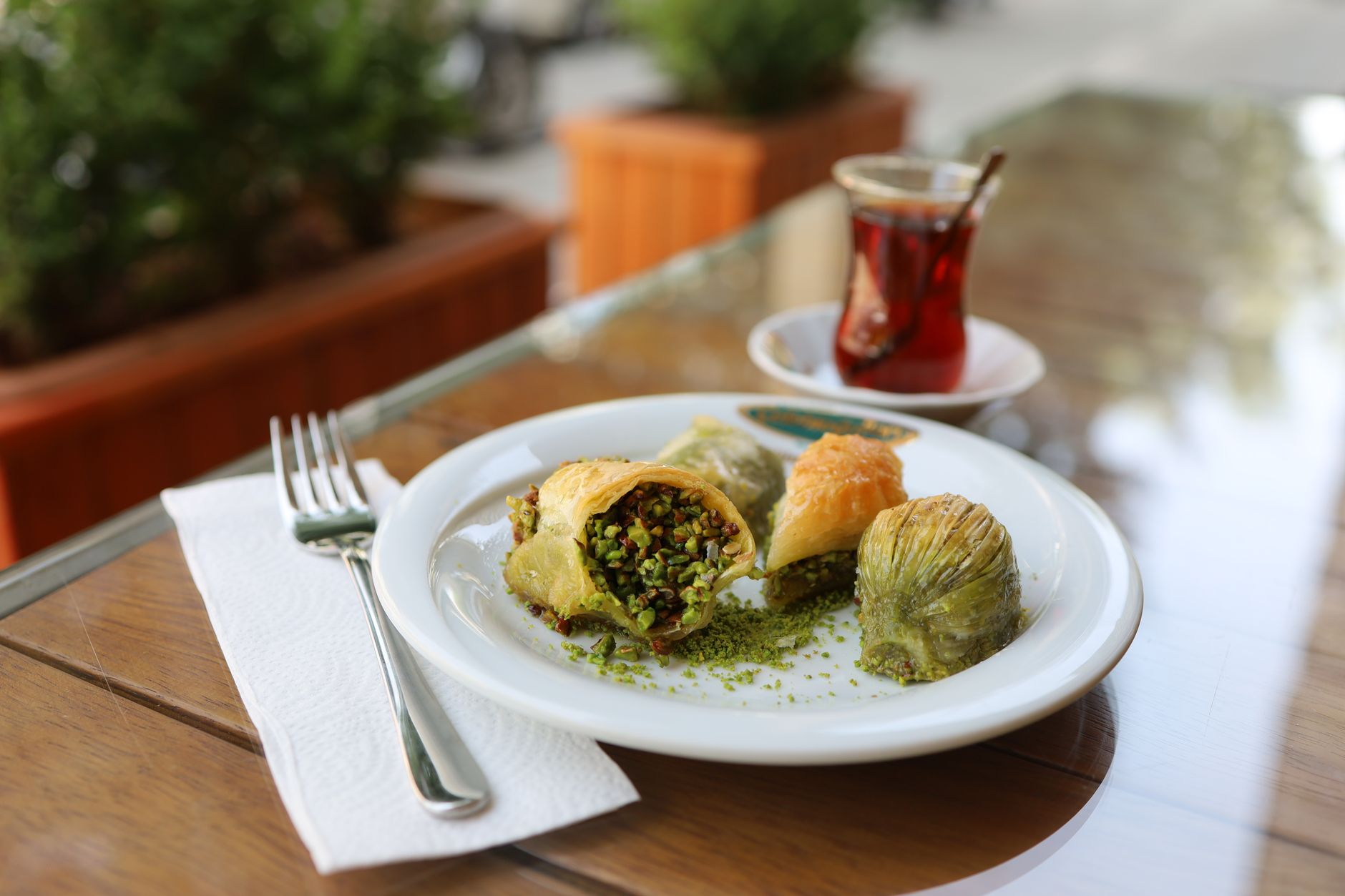 Traditionelles türkisches Baklava mit Pistazien serviert neben einem Glas türkischem Tee.