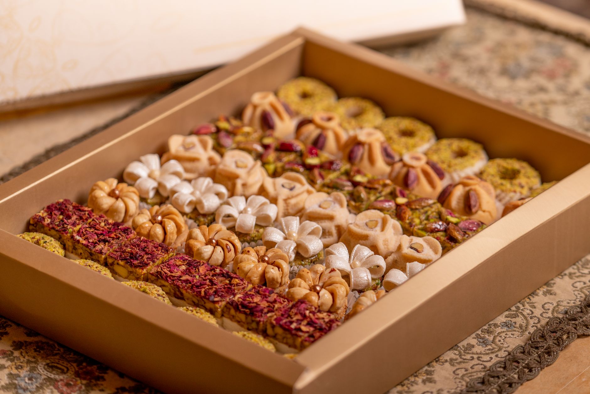 Eine elegant arrangierte Geschenkbox mit verschiedenen orientalischen Gebäcken, verziert mit Nüssen und Blüten.