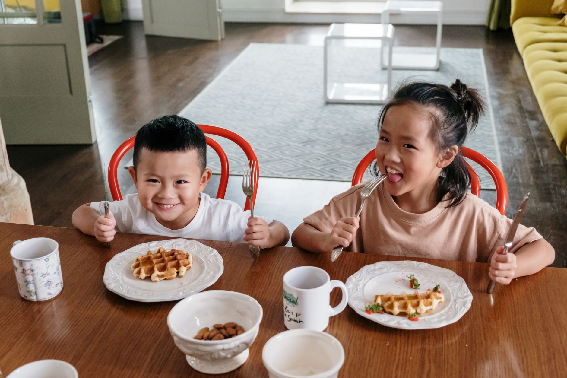 Zwei glückliche Kinder sitzen am Tisch und teilen sich ein leckeres Frühstück