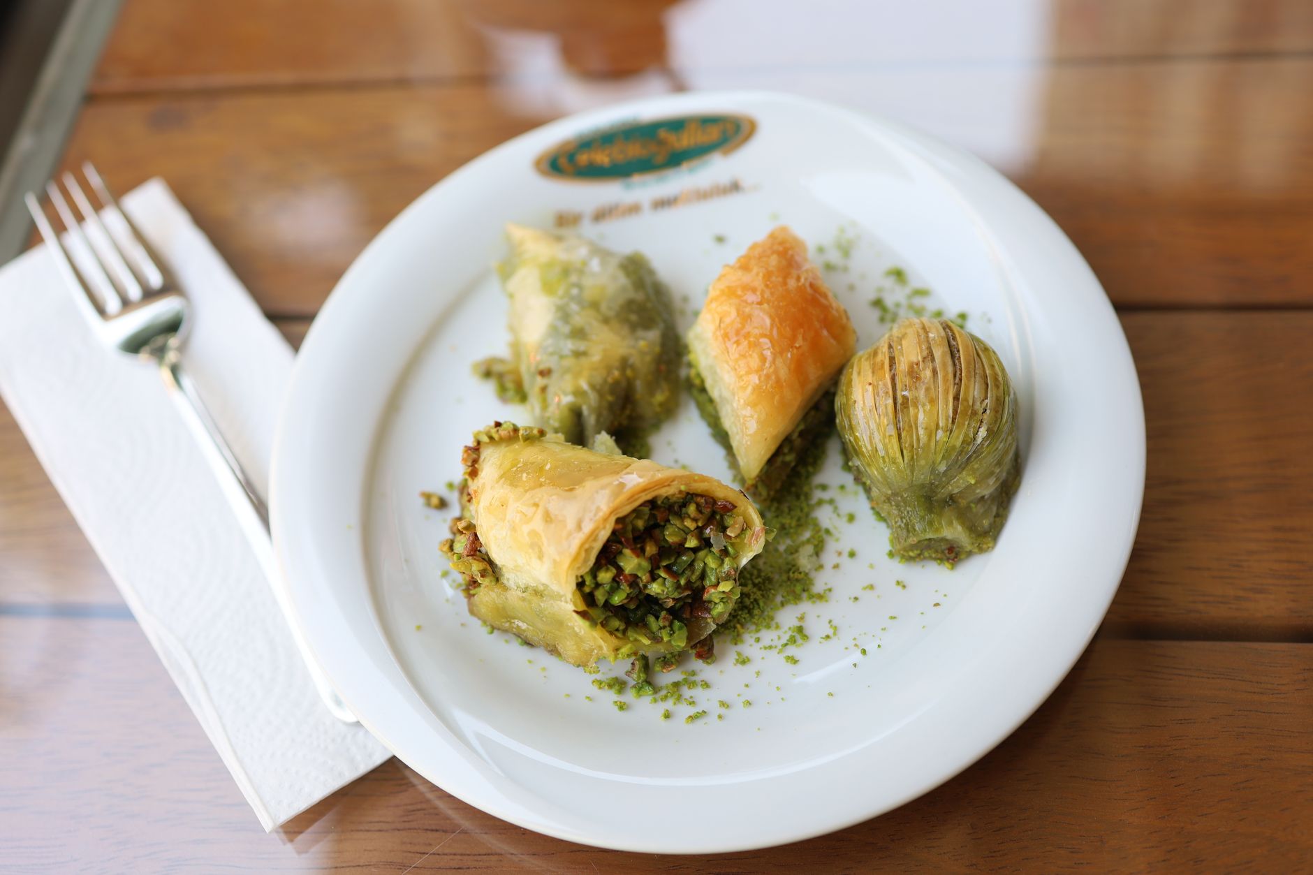 Eine Auswahl verschiedener türkischer Baklava-Spezialitäten mit grünen Pistazien auf einem Teller serviert.