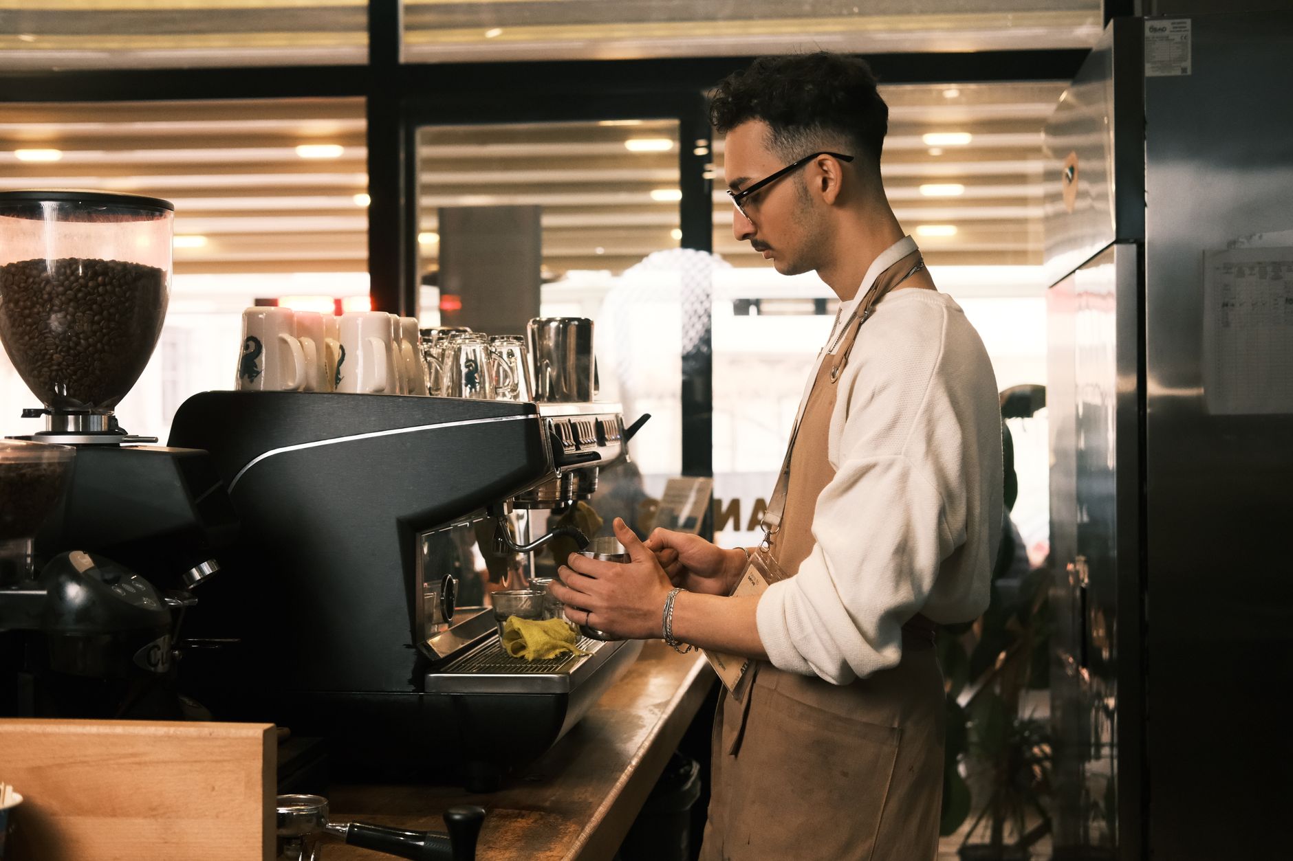 Ein Barista bereitet in einem modern eingerichteten Café sorgfältig warmen Kaffee zu.