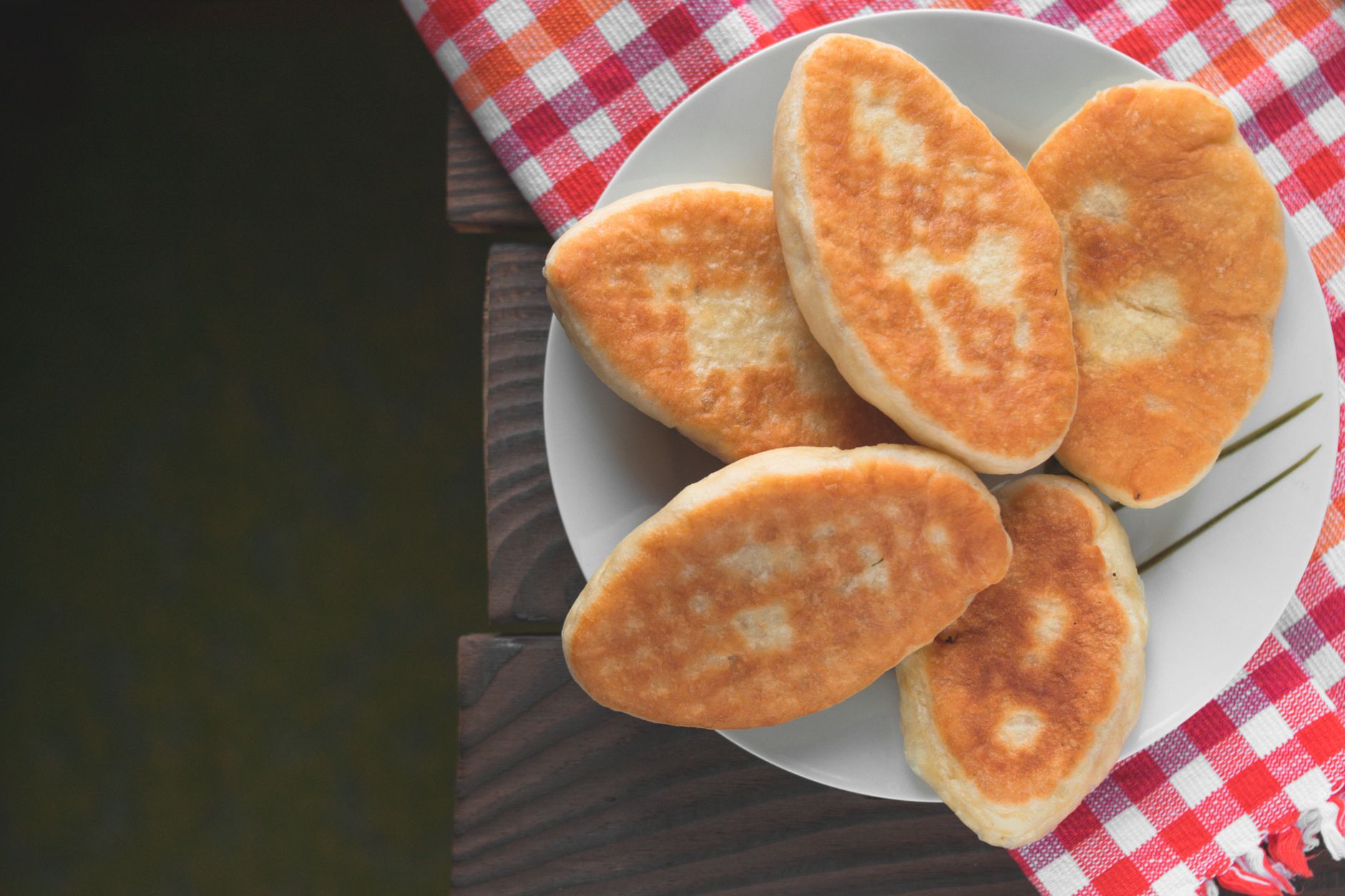Goldgelb frittierte Hefeteigbällchen ansprechend auf einem Teller mit kariertem Tuch angerichtet