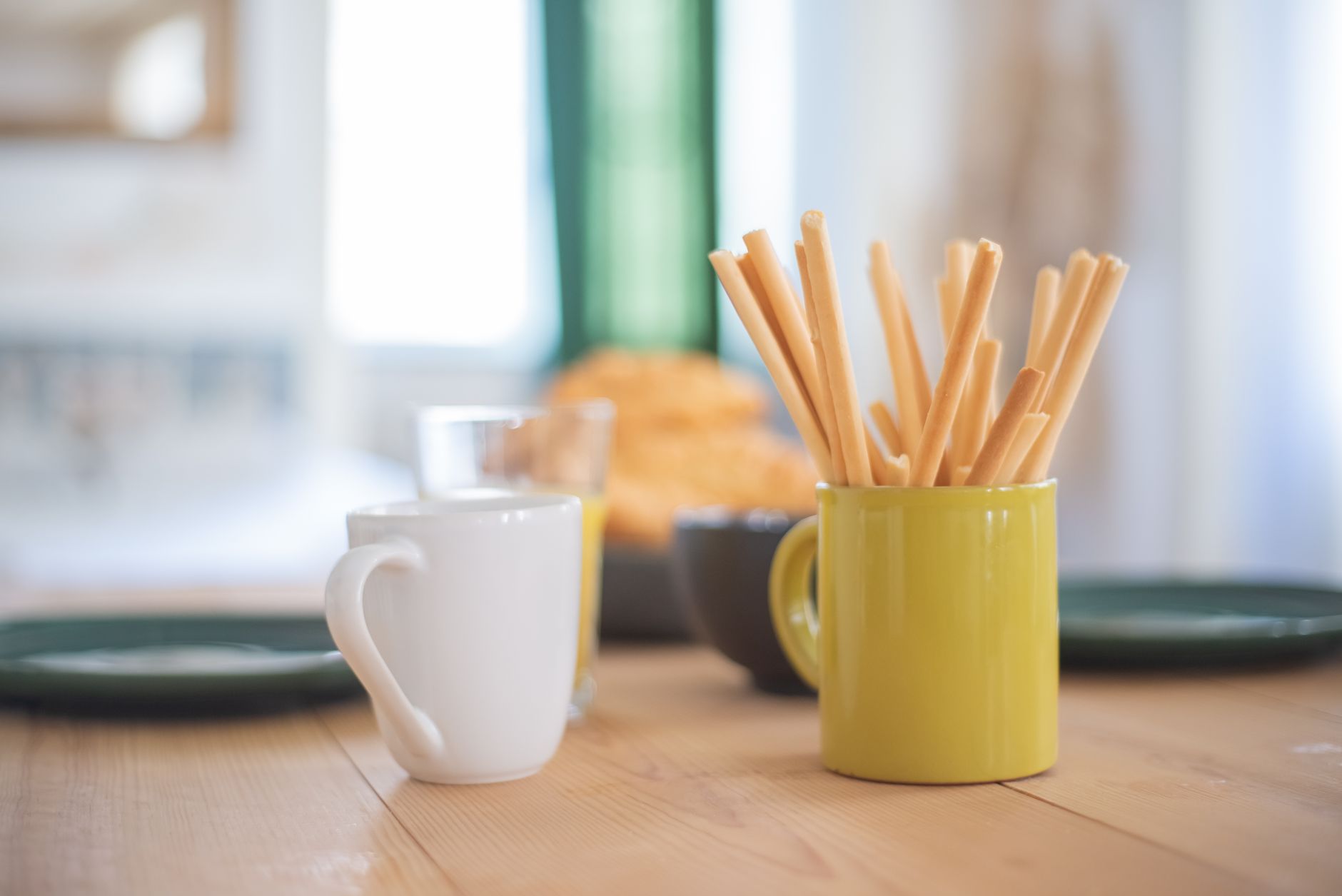 Eine gemütliche Frühstückssituation mit Tassen und Gebäck auf einem Holztisch, ideal für eine Arbeitspause.