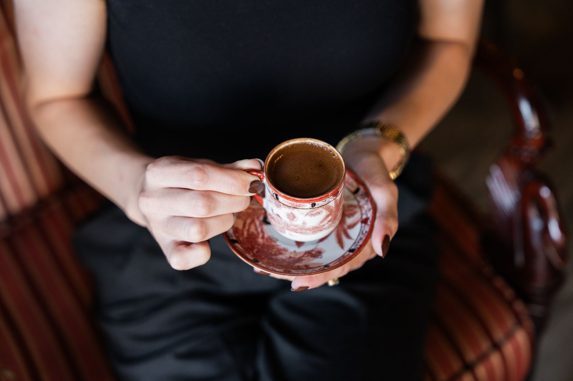 Eine Frau hält eine kunstvoll verzierte traditionelle Tasse mit frisch gebrühtem türkischen Kaffee in den Händen.