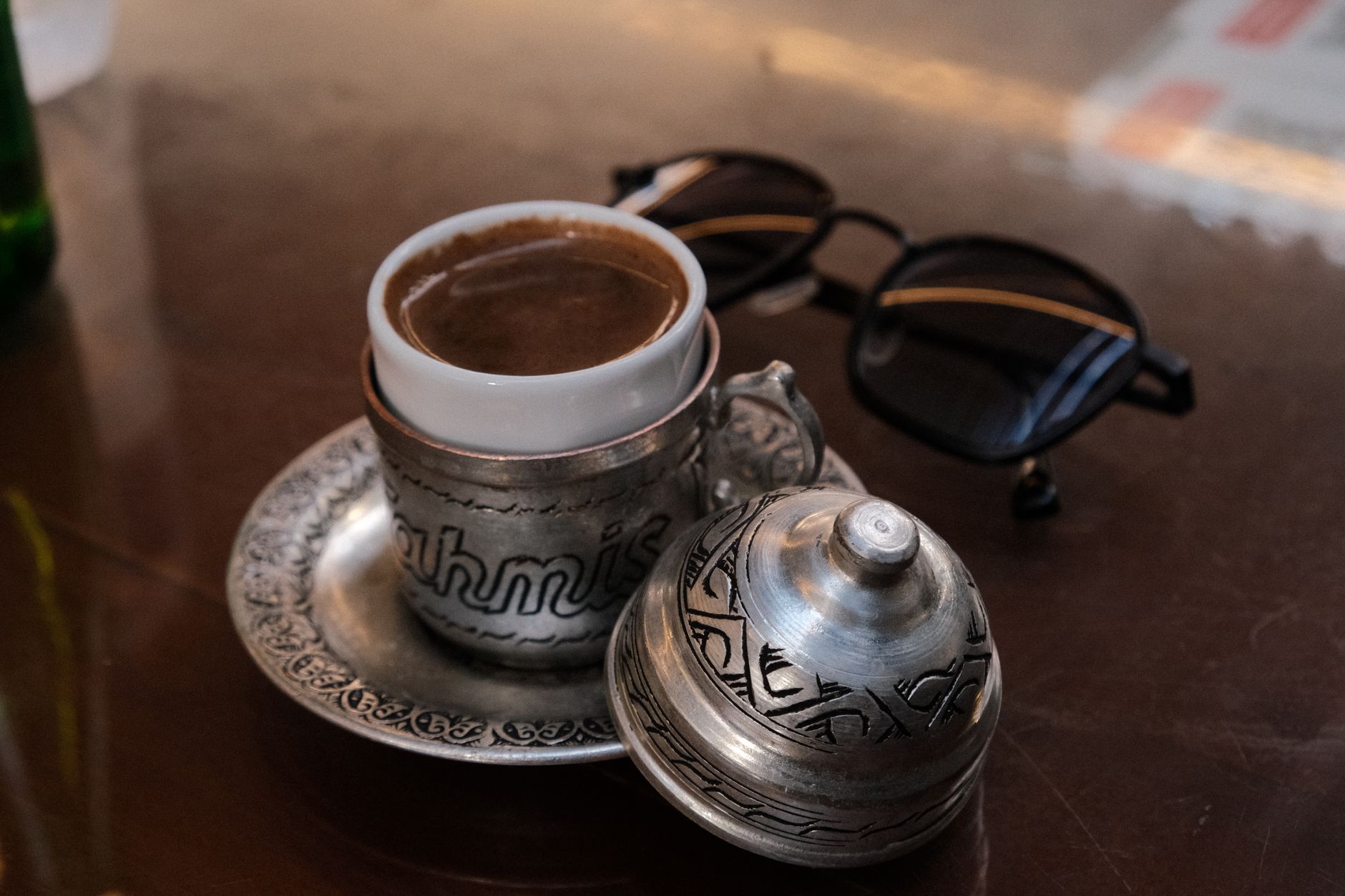 Ein traditioneller türkischer Mokka in einer verzierten Tasse, serviert mit einem Glas Wasser und einem Lokum auf einem silbernen Tablett.